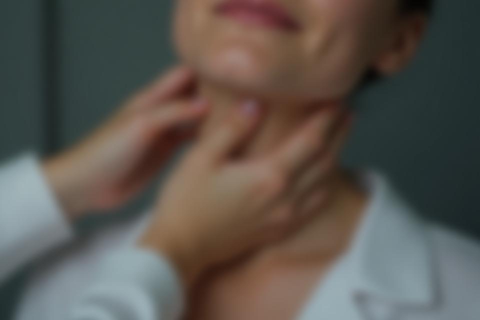Gros plan d'une main tenant délicatement la gorge, symbolisant le soin vocal, le soutien et le bien-être.